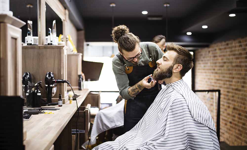Barber atenent i afaitant a un client en el seu local
