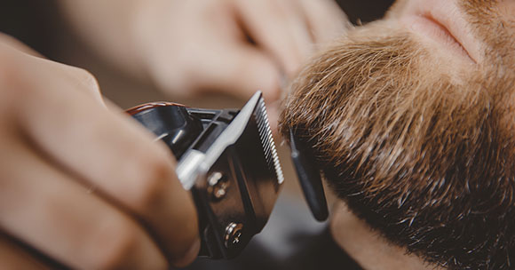 Barber retallant barba a un client